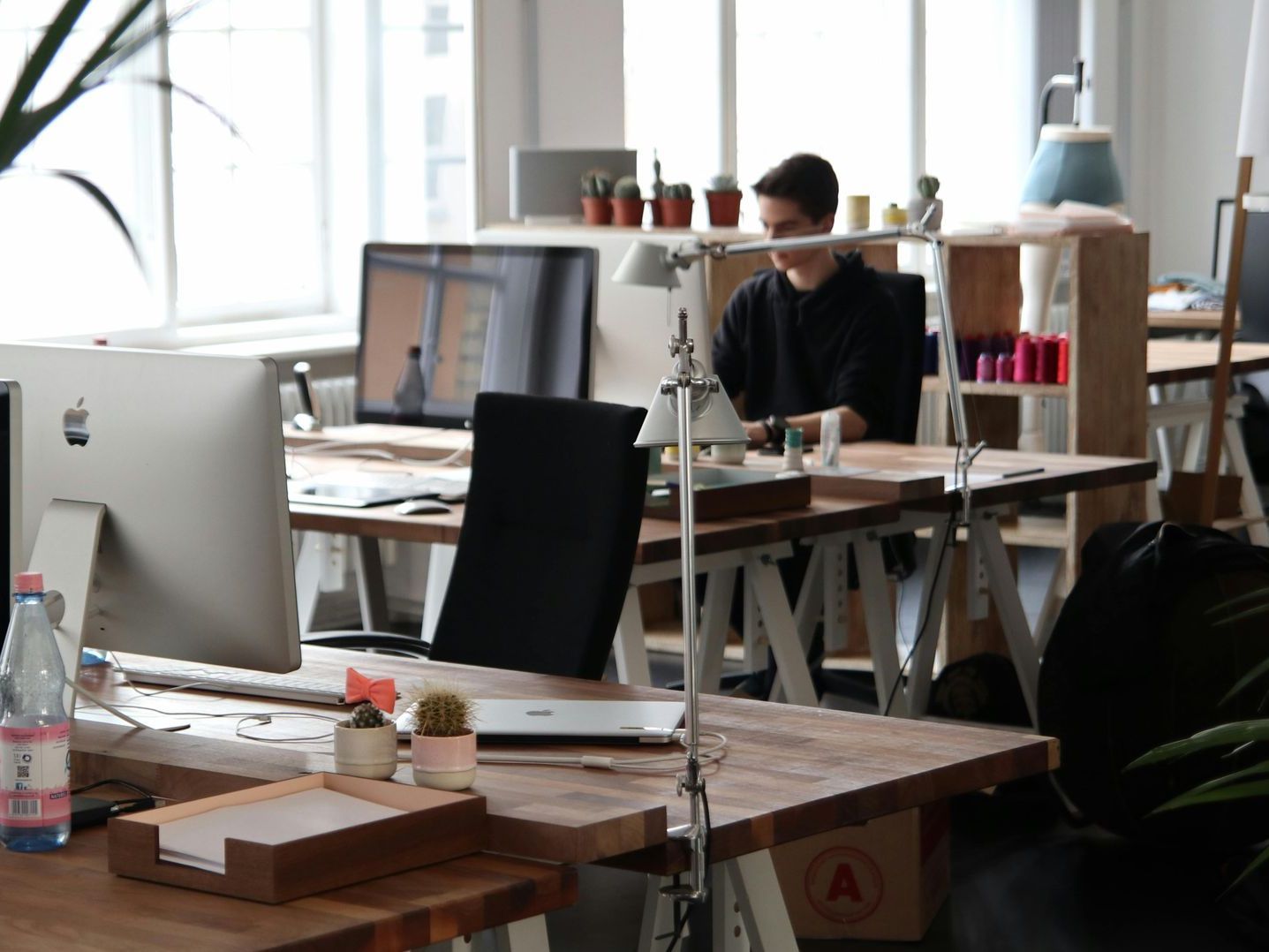 A man sits at a desk with an apple computer