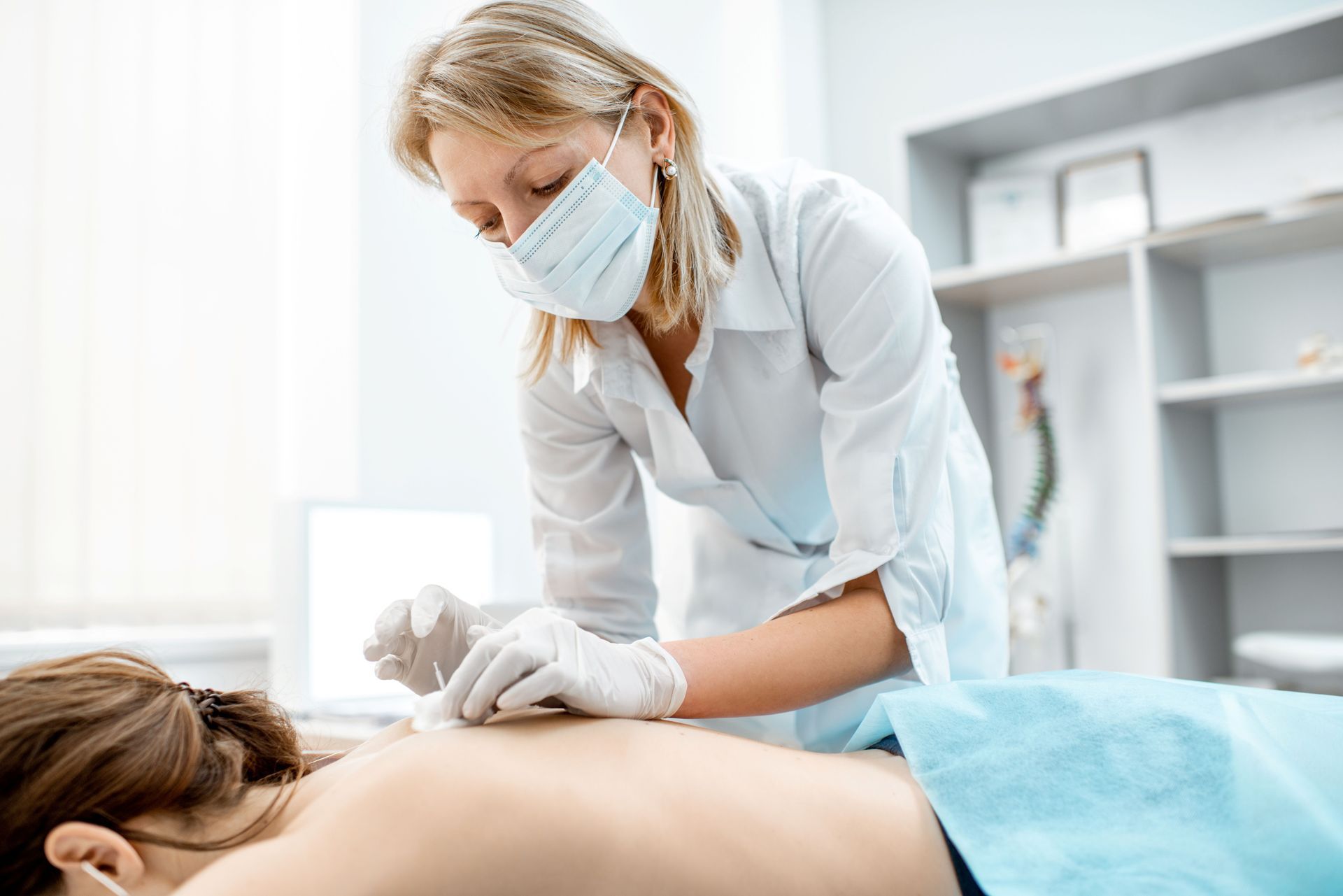 A medical professional treating a patient's back at a specialized acupuncture clinic.
