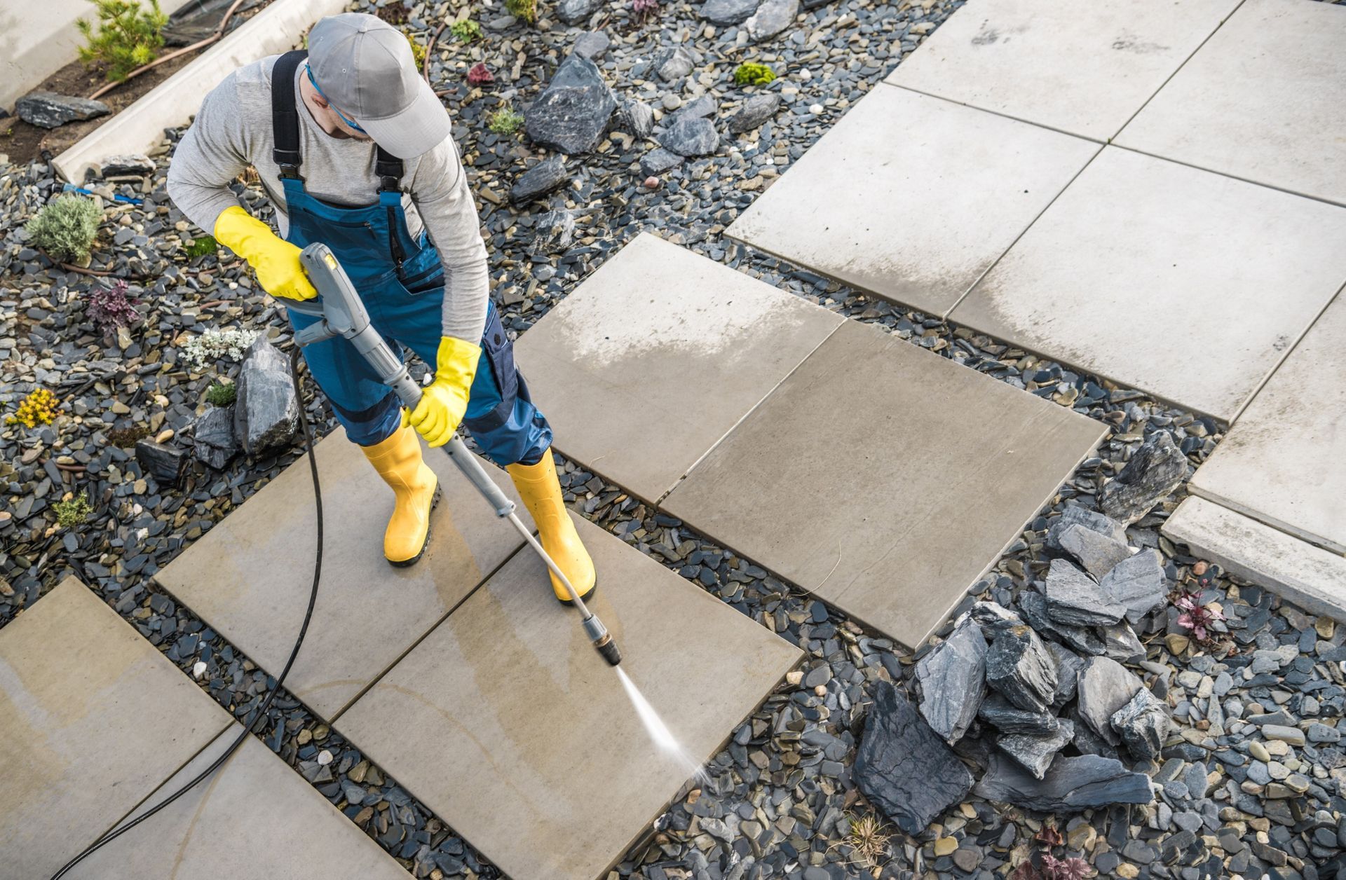 A man is cleaning a patio with a high pressure washer.
