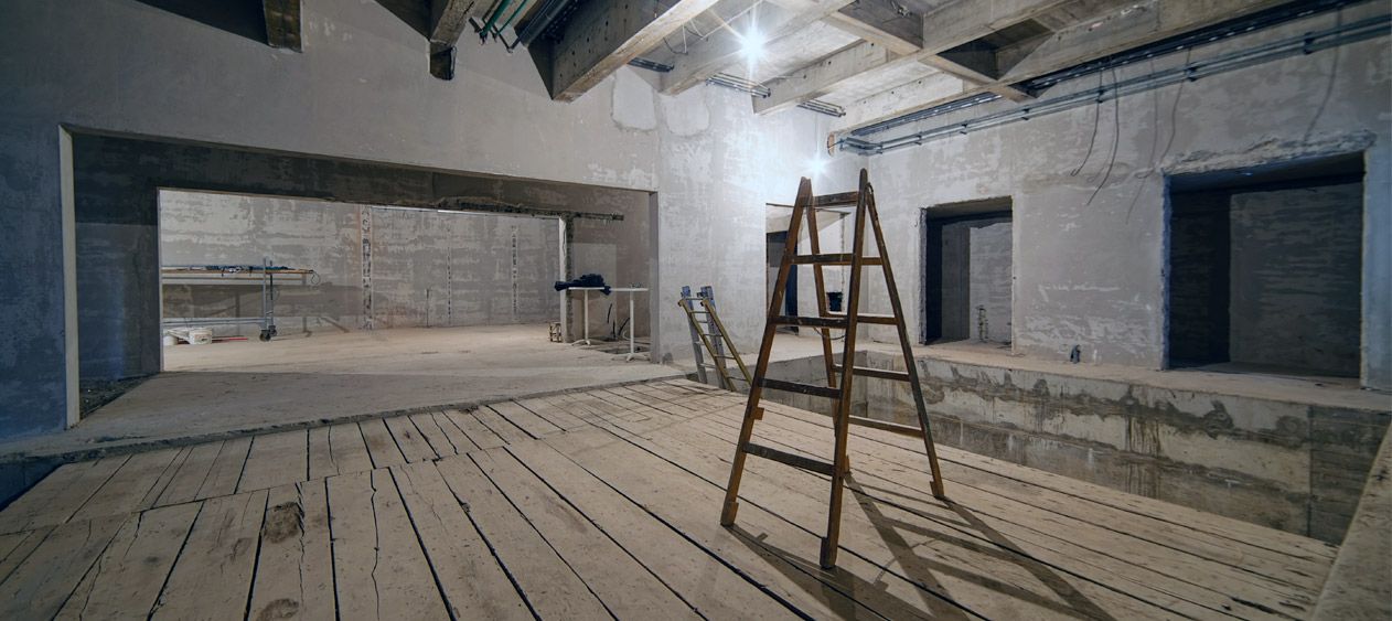 An empty room with a ladder in the middle of it.