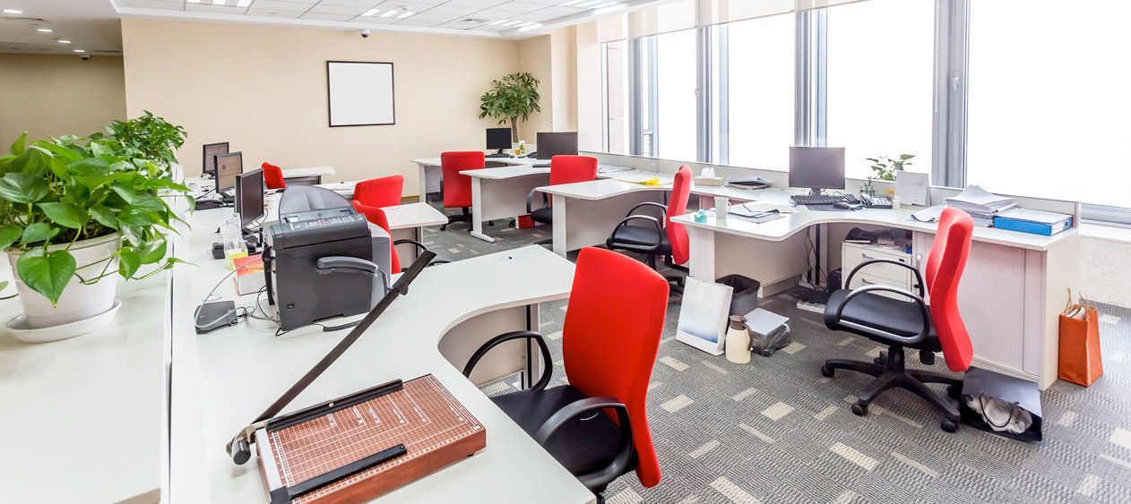 A large empty office with lots of desks and chairs.