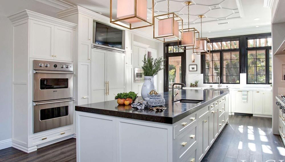 A kitchen with white cabinets, stainless steel appliances, and a large island.