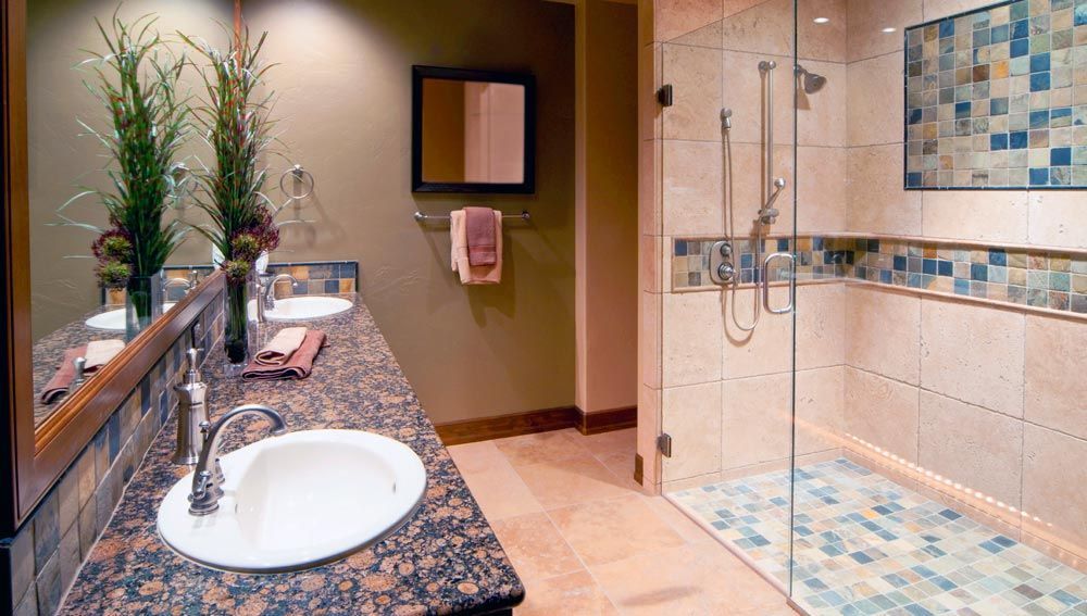 A bathroom with two sinks and a walk in shower.