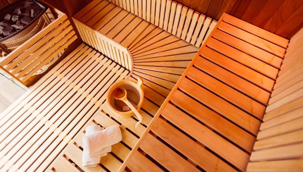 A wooden sauna with a bowl of honey and a spoon on the floor.