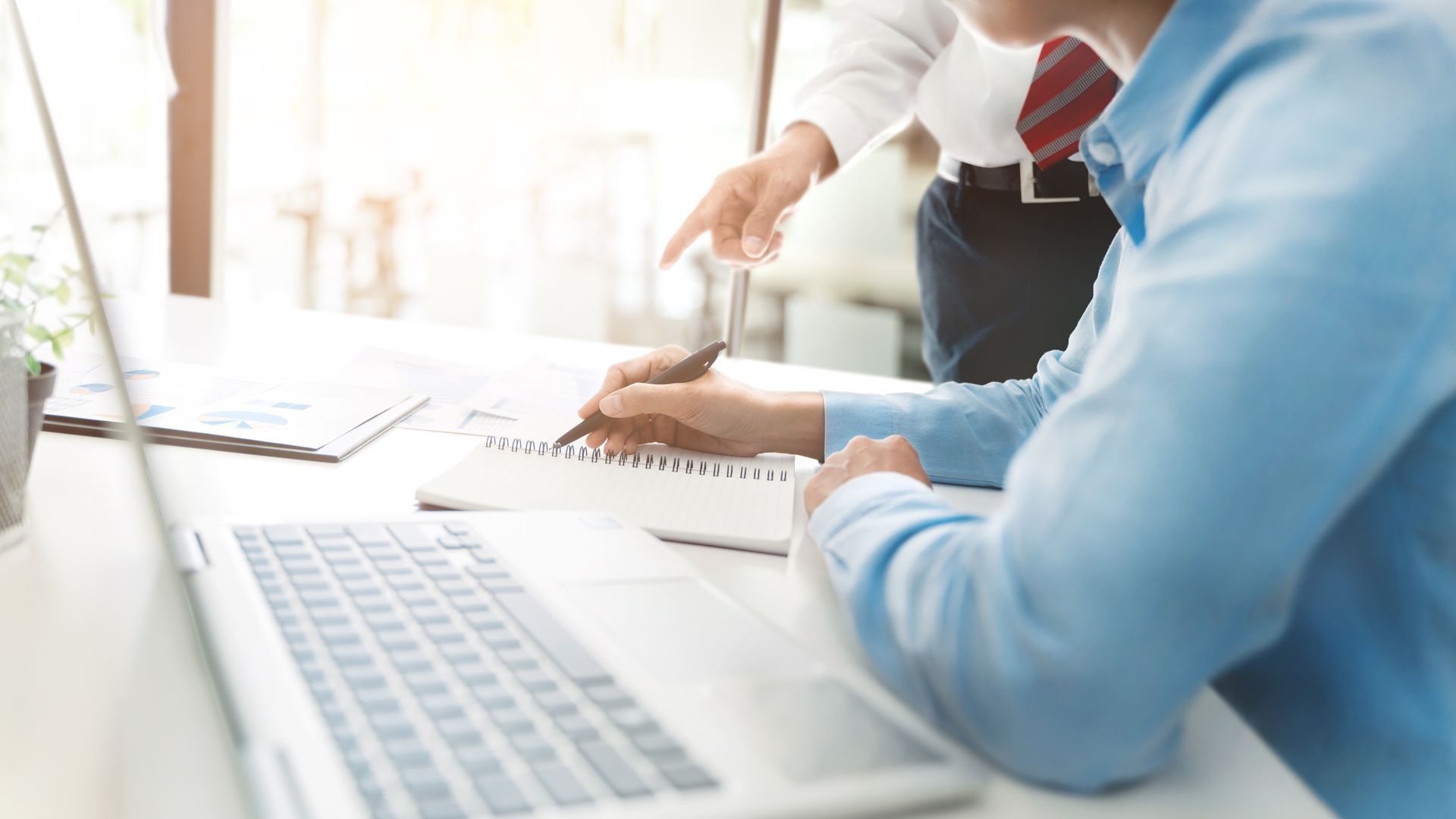Business advisor guiding a client through notes and reports during a desk consultation.