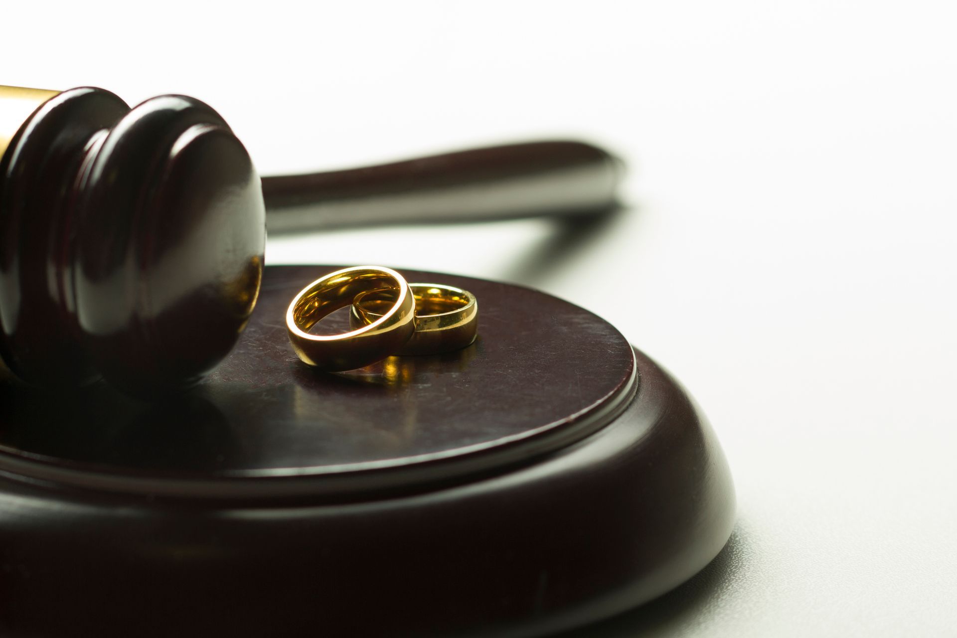 Judge gavel with gold wedding rings symbolizing divorce law, marriage legal proceedings concept.