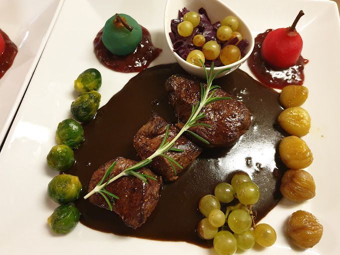 Une assiette blanche garnie de sauce à la viande, de raisins et de choux de Bruxelles