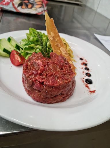 Une assiette blanche surmontée d'un morceau de viande et de légumes.