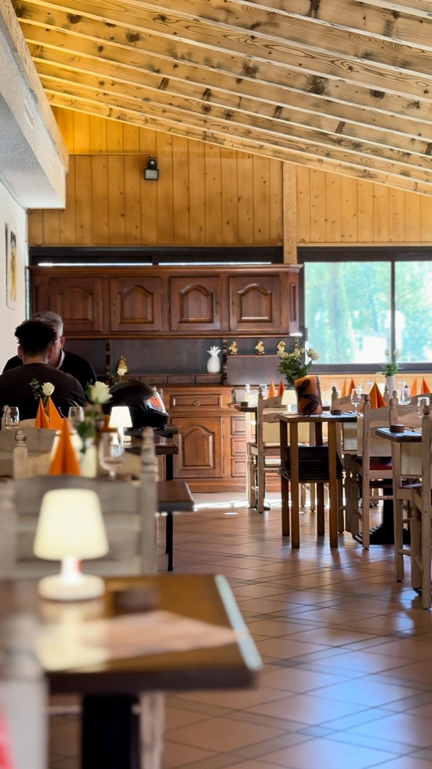 Un restaurant avec des tables et des chaises et une cuisine en arrière-plan.