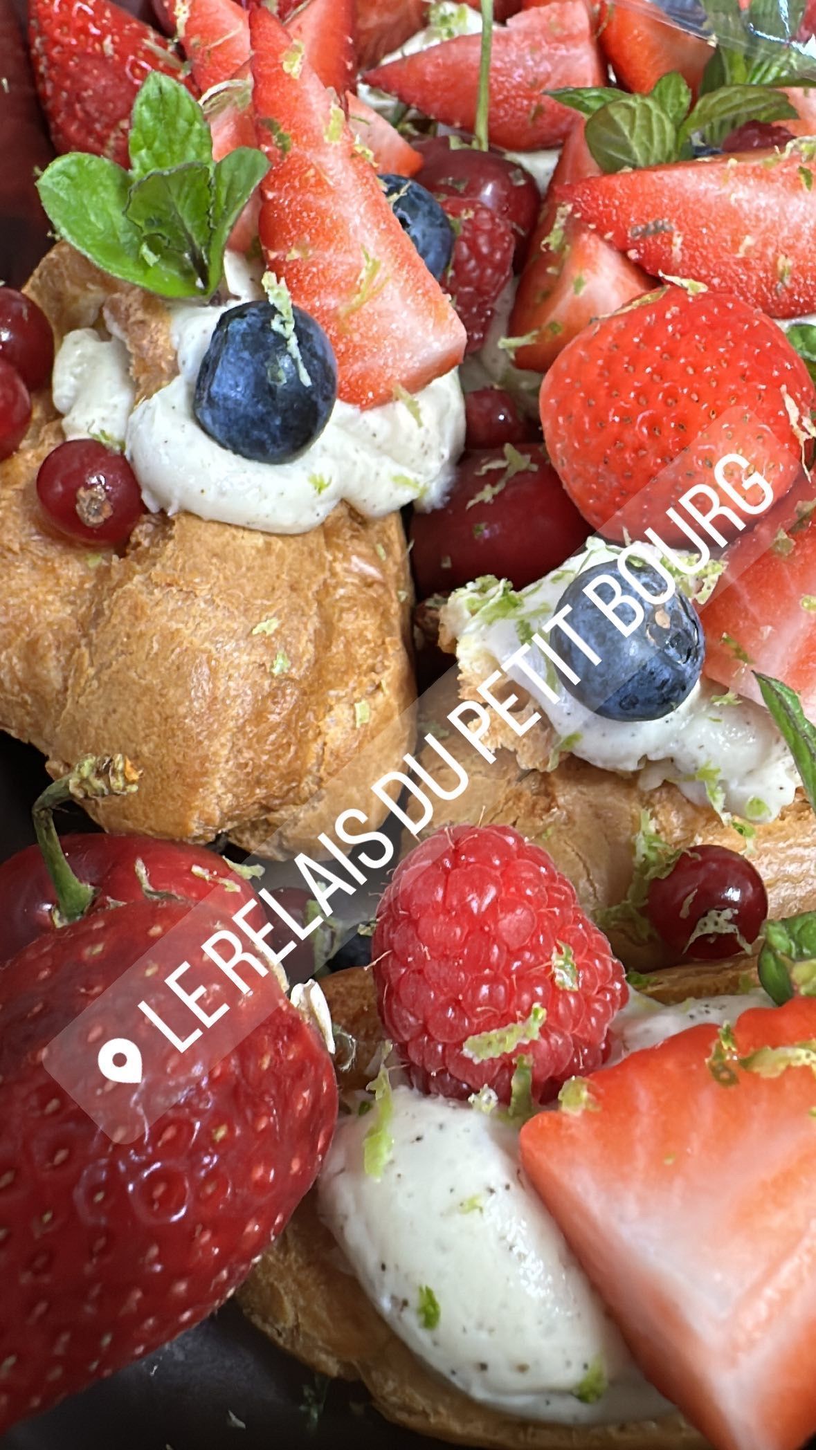 Un gros plan d'une assiette de nourriture avec des fraises, des framboises, des myrtilles et de la crème fouettée.