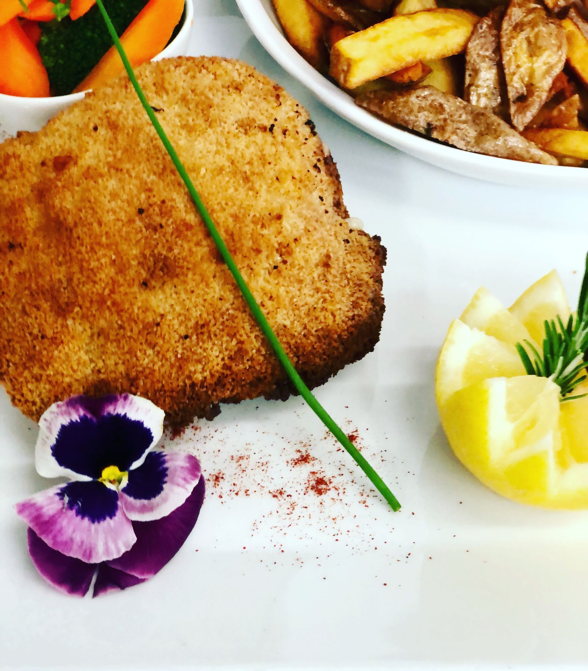 Une assiette de nourriture avec une fleur violette et une tranche de citron