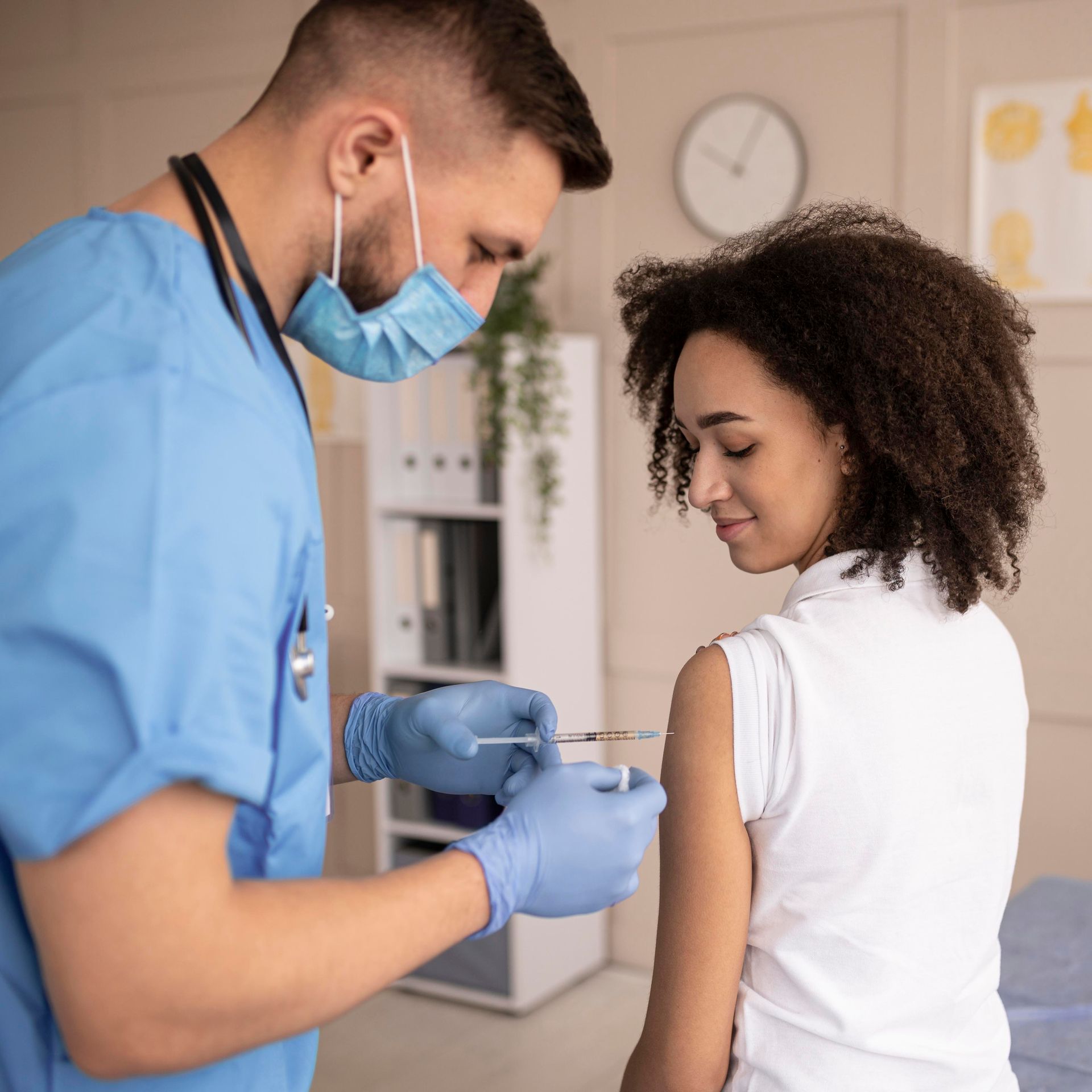A nurse is giving a woman a vaccine in her arm.