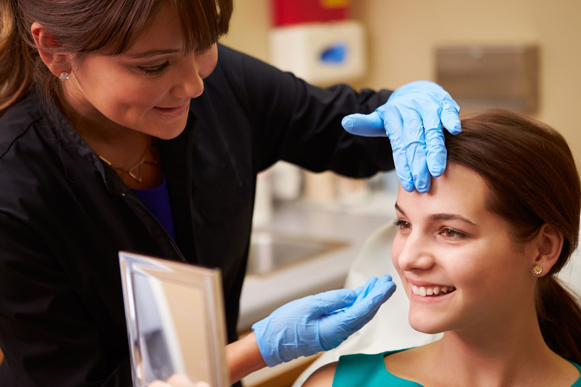 A woman is getting her face examined by a doctor.