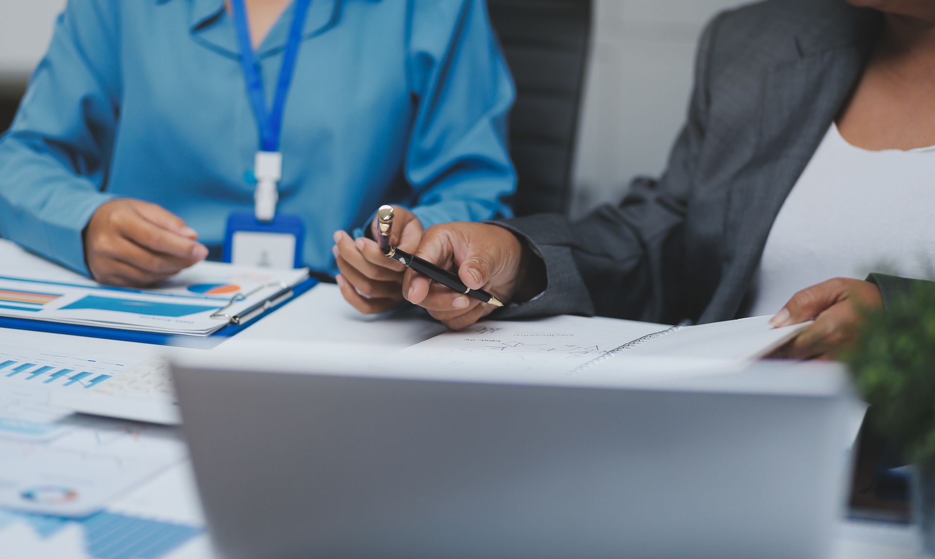 A partial view of an auditor and an accountant team working in an office over paperwork.