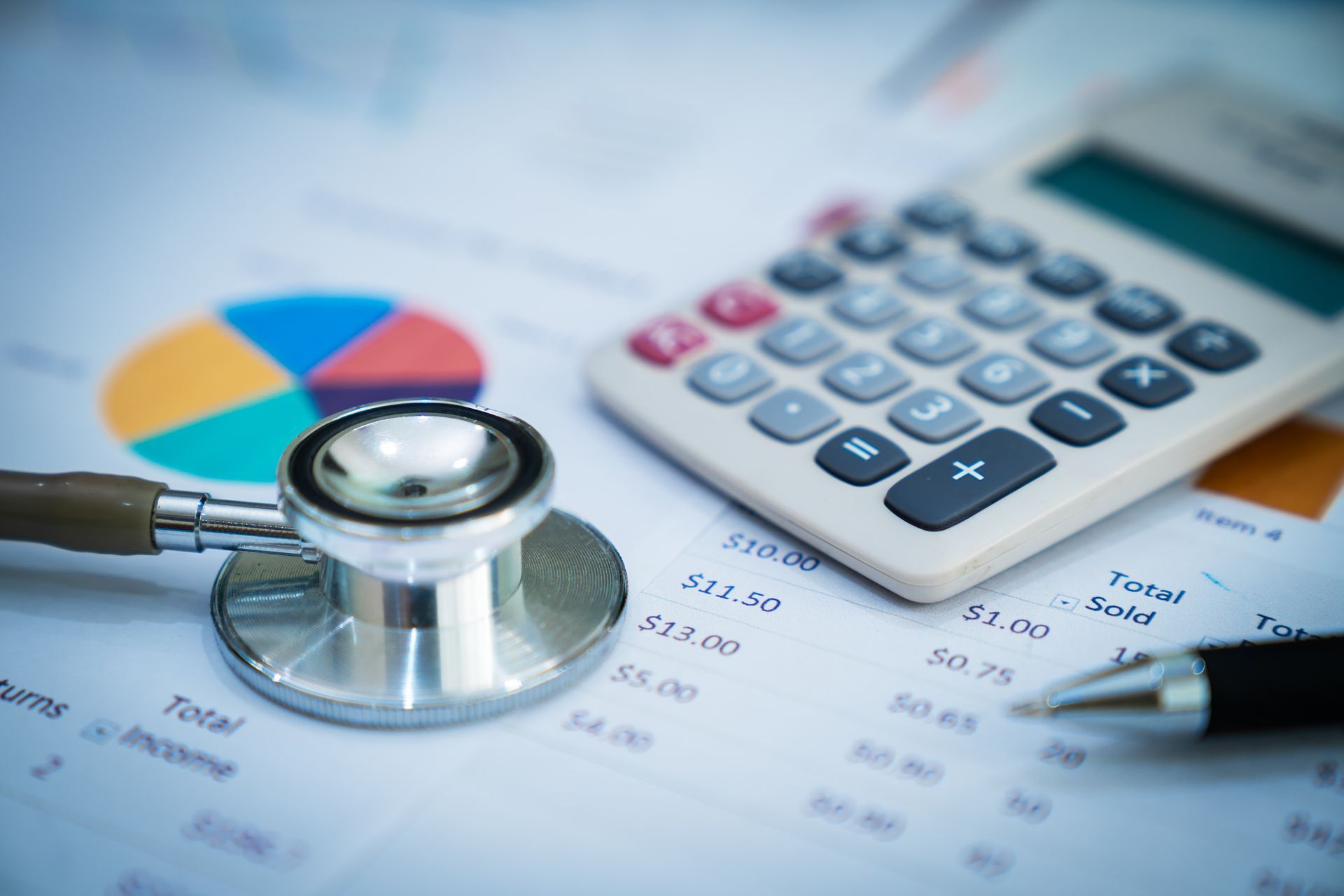 Stethoscope and calculator on financial documents with pie chart.
