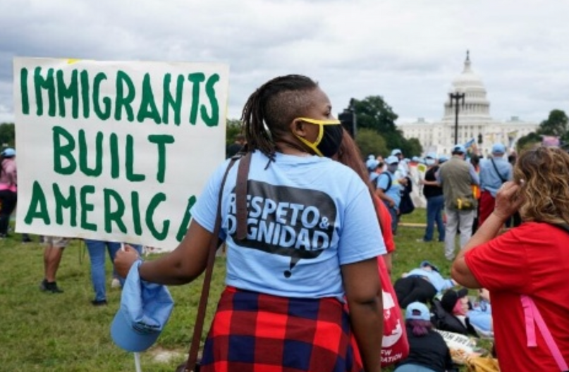 A woman holding a sign that says immigrants built america