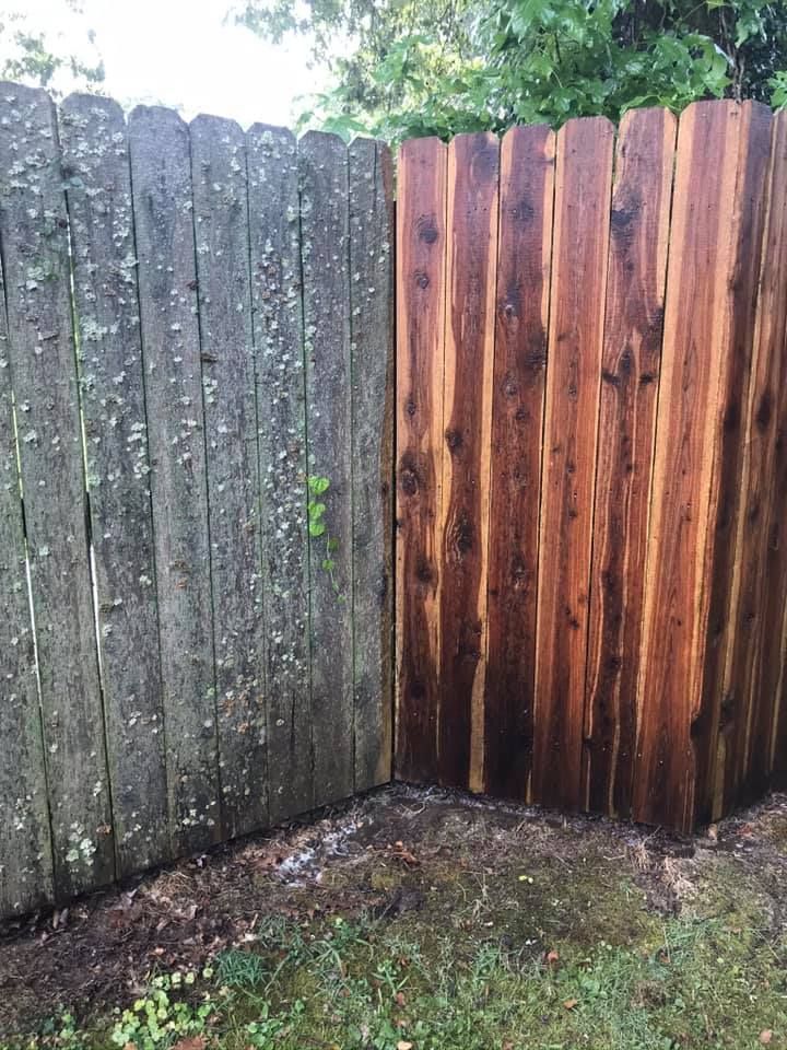 A weathered wooden fence half cleaned, showing the contrast between faded and freshly stained wood.