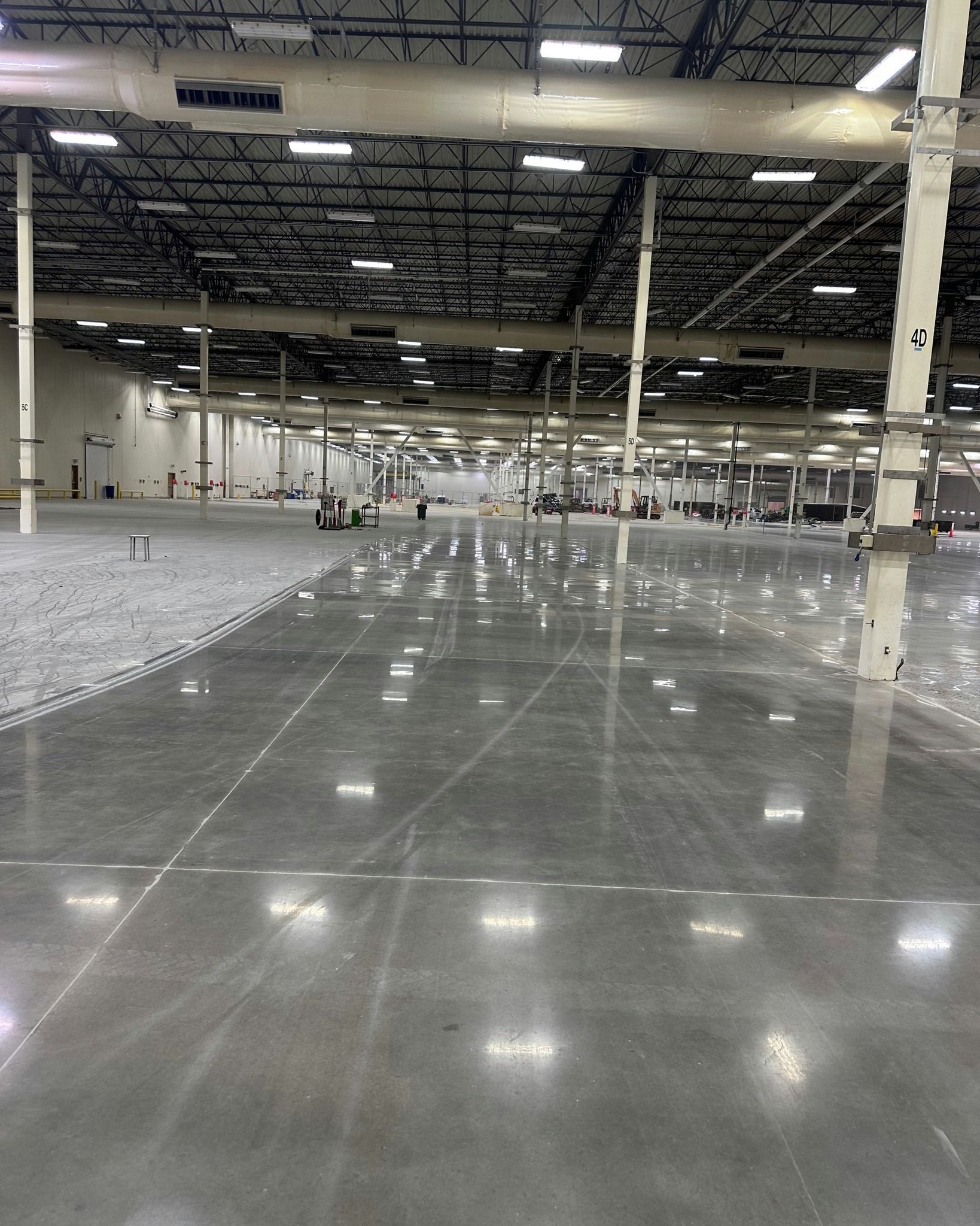 Large, empty warehouse with a polished concrete floor reflecting overhead lights.