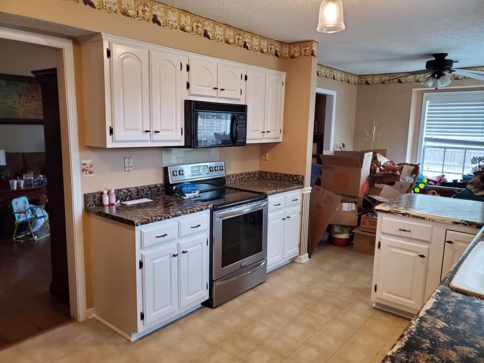 White kitchen cabinets with stainless steel appliances and dark countertops.