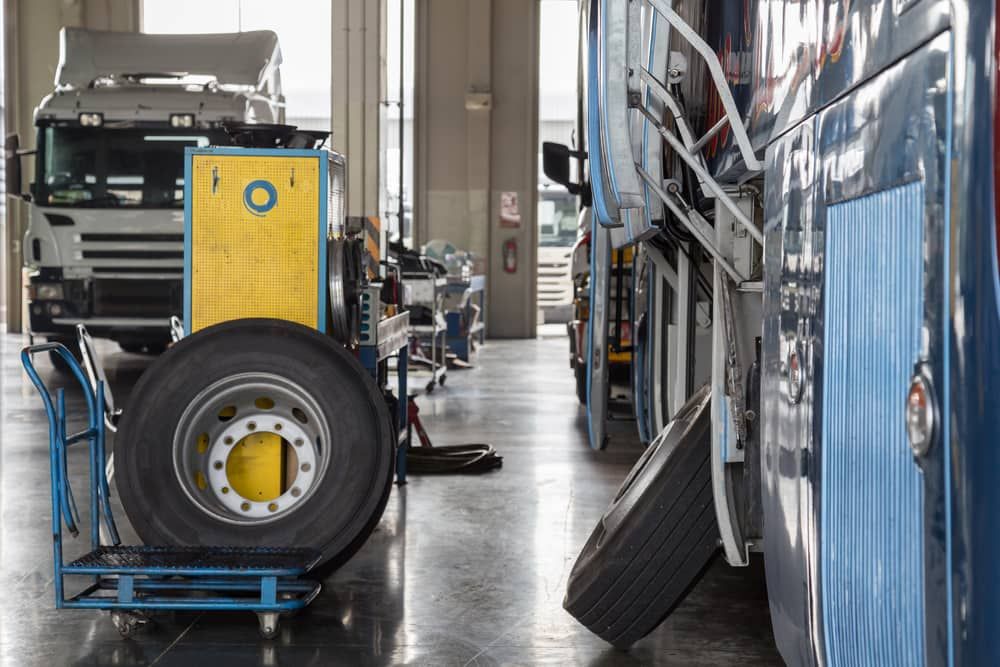 A Truck Is Being Repaired in A Garage with A Tire on A Cart — Coast Mechanical Services In Berkeley Vale, NSW