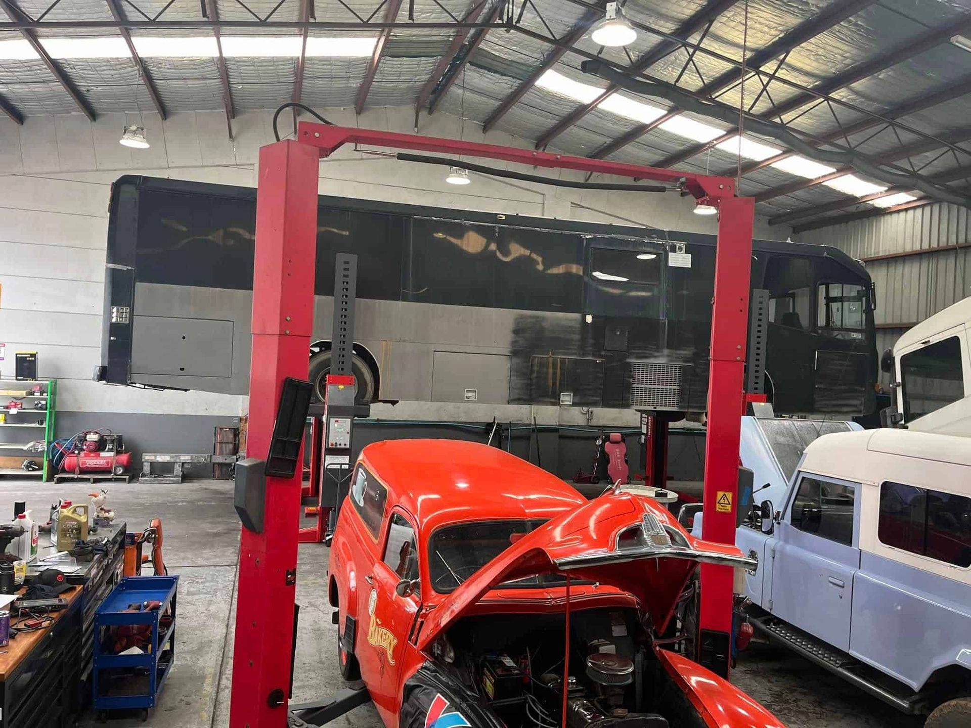 A Red Car Is Sitting on Top of A Red Lift in A Garage — Coast Mechanical Services In Berkeley Vale, NSW
