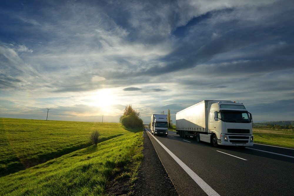 Two Semi Trucks Are Driving Down a Highway Next to A Grassy Field — Coast Mechanical Services In Berkeley Vale, NSW
