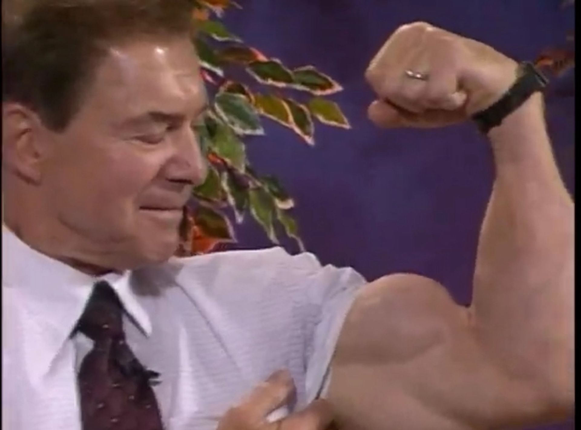 A man in a suit and tie is flexing his arm