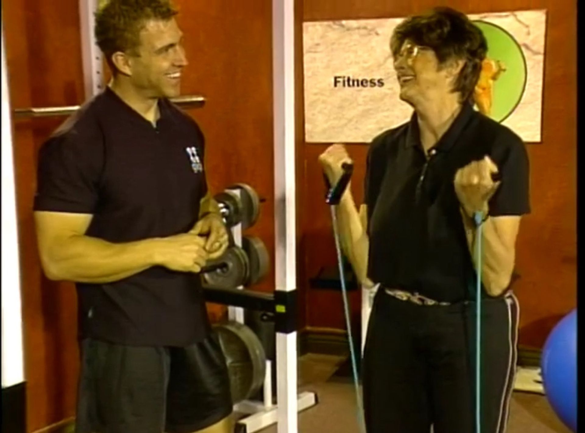 Tom Wright and a woman are standing in front of a sign that says fitness