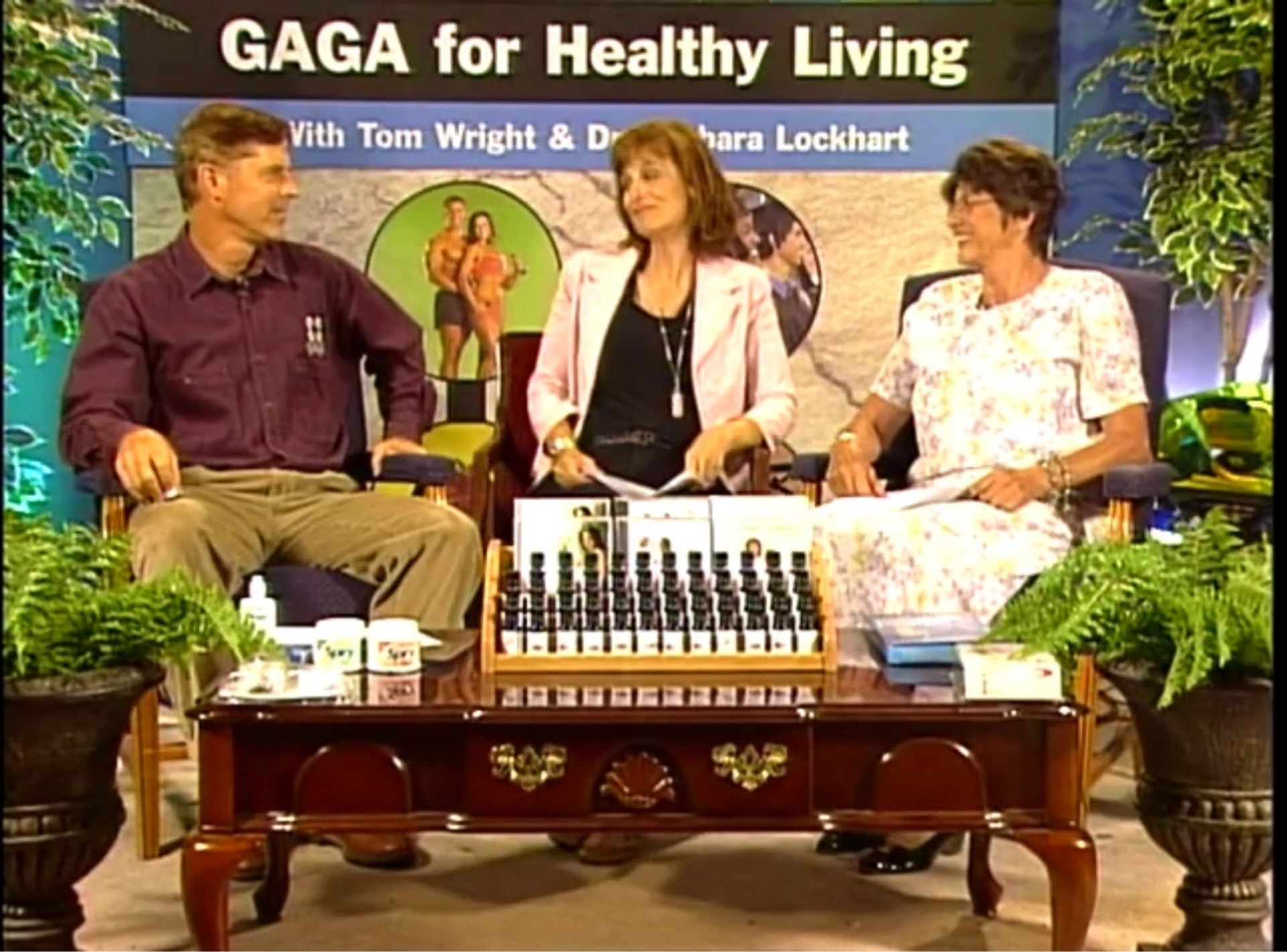 Three people sit at a table in front of a sign that says gaga for healthy living