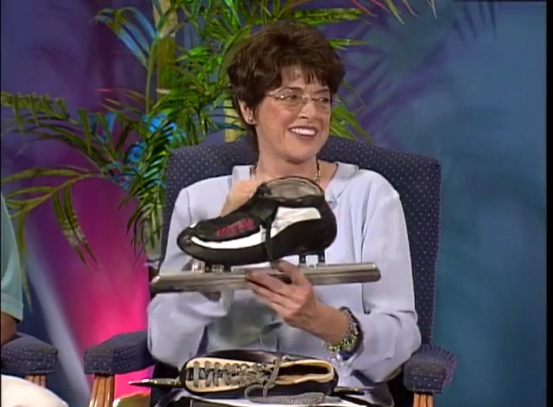 A woman is sitting in a chair holding a pair of ice skates