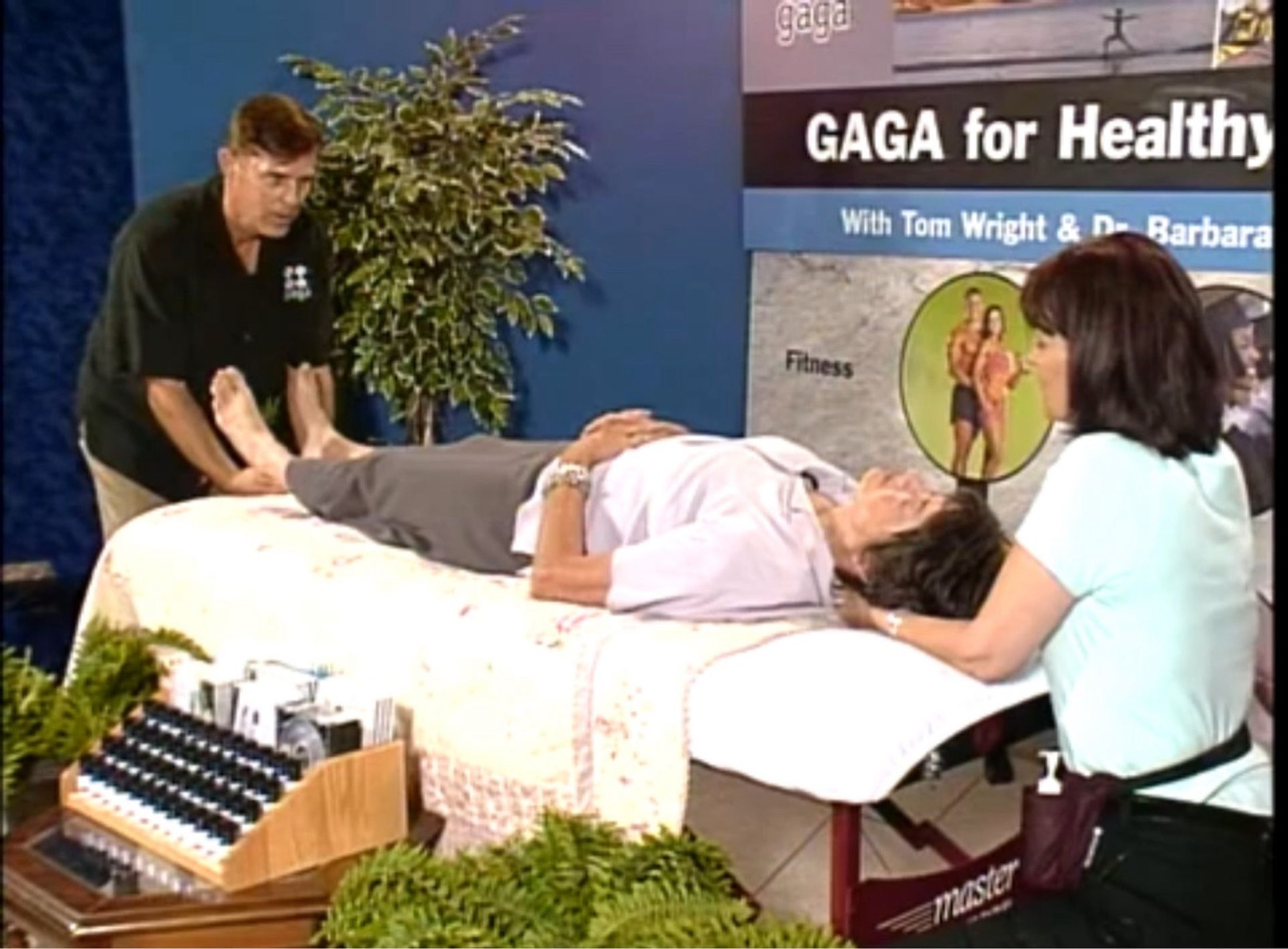 A woman is laying on a massage table in front of a sign that says gaga for health