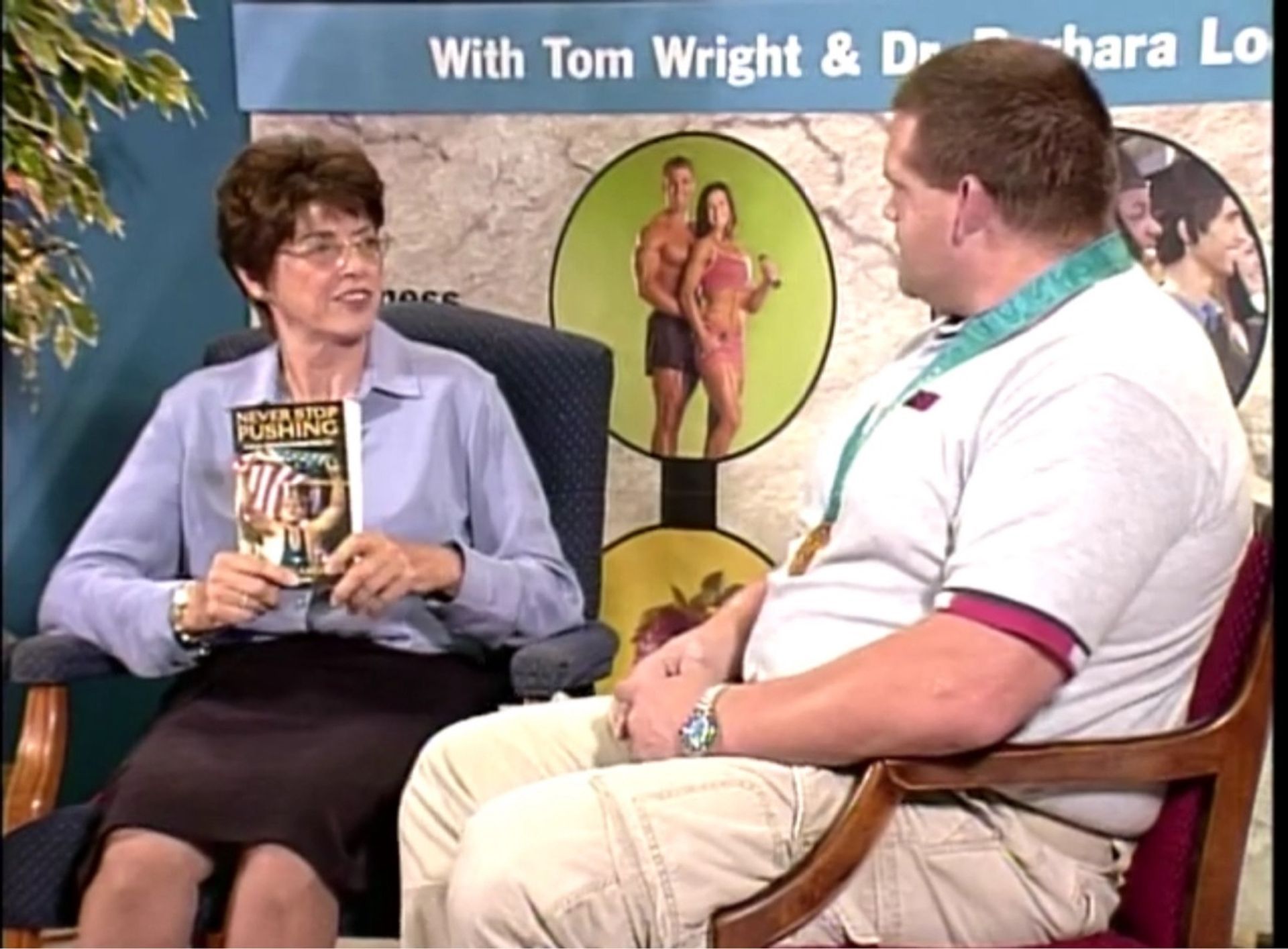 A man and a woman are sitting in front of a sign that says tom wright