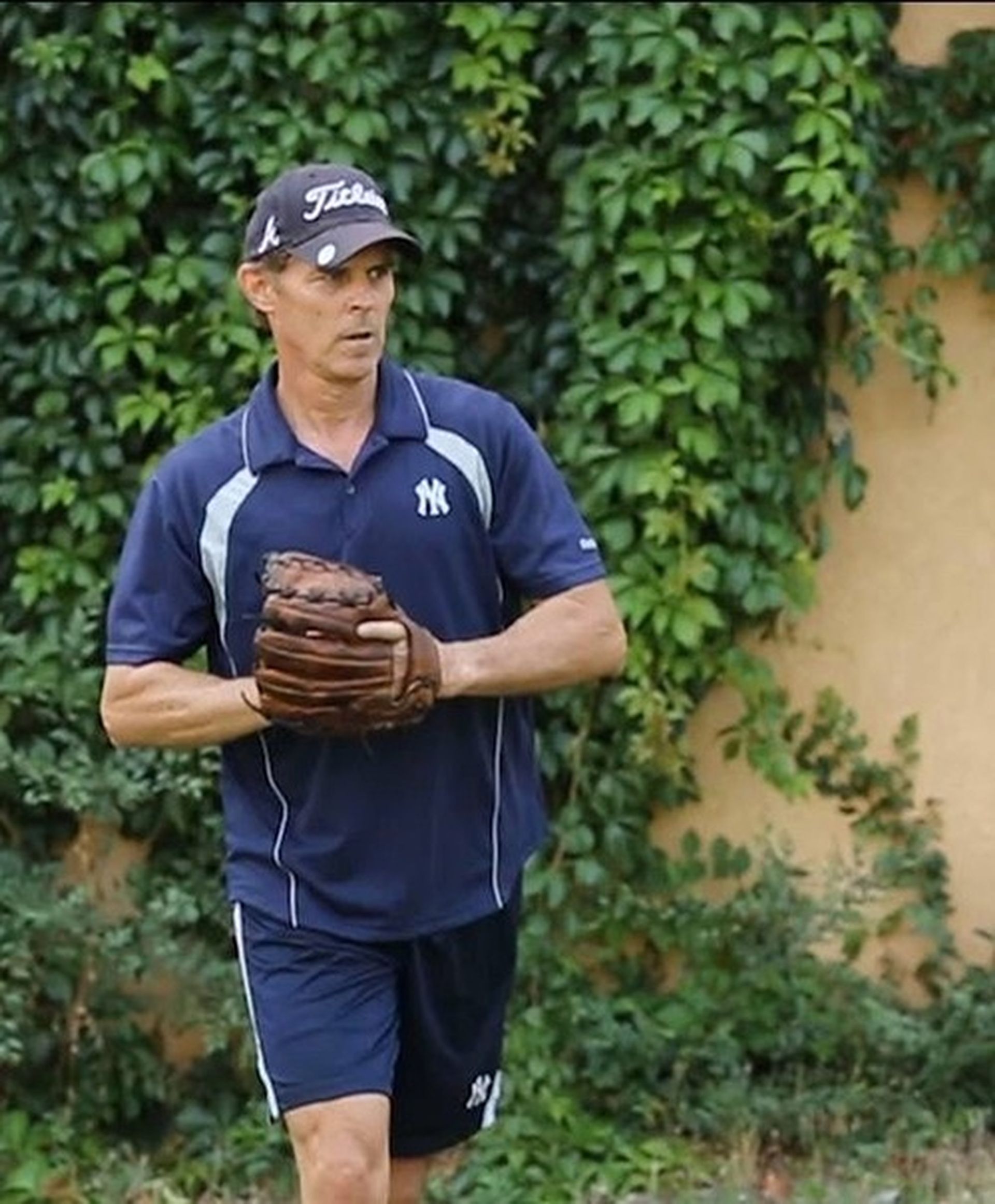 Tom Wright is wearing a hat that says Titleist is holding a baseball glove