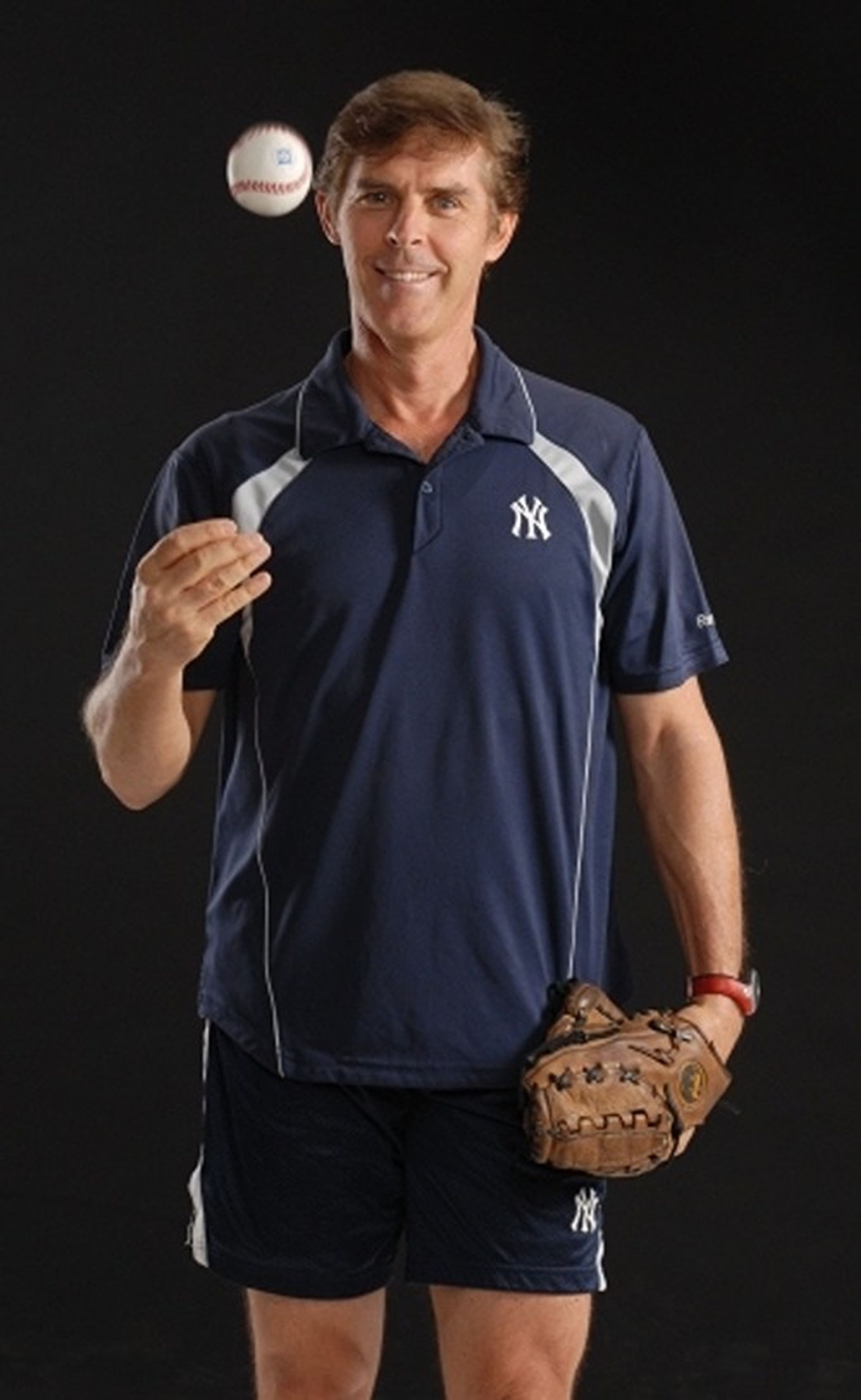 Tom Wright in a blue shirt is holding a baseball and a baseball glove.