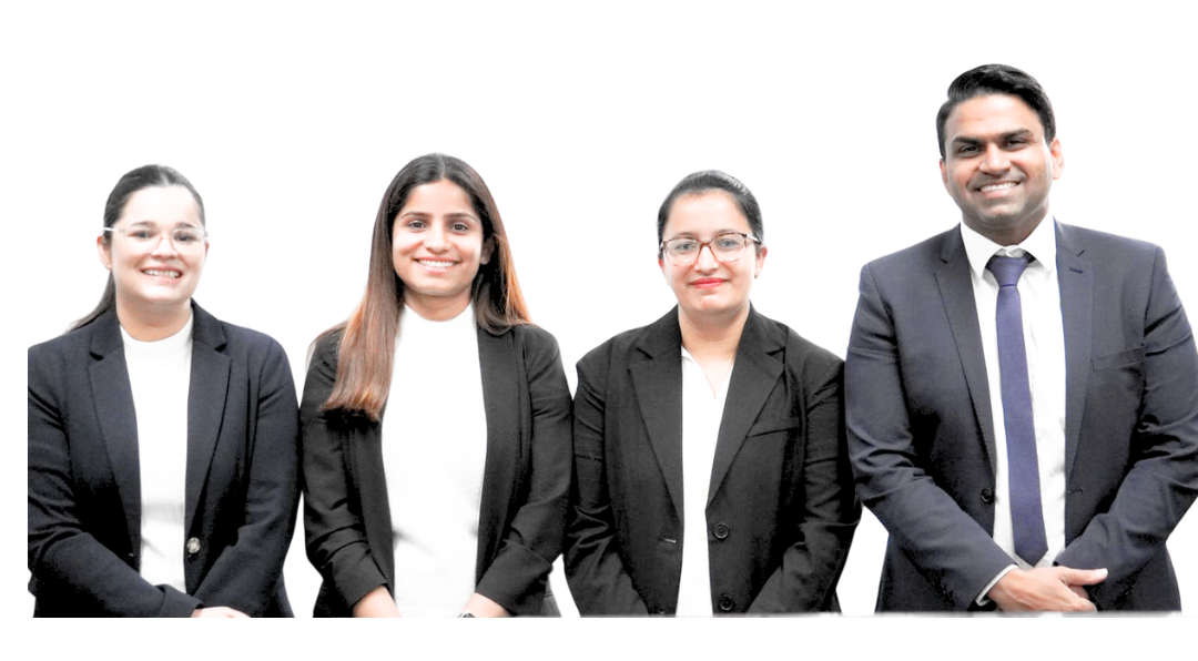 Four professionals in suits smiling at the camera.
