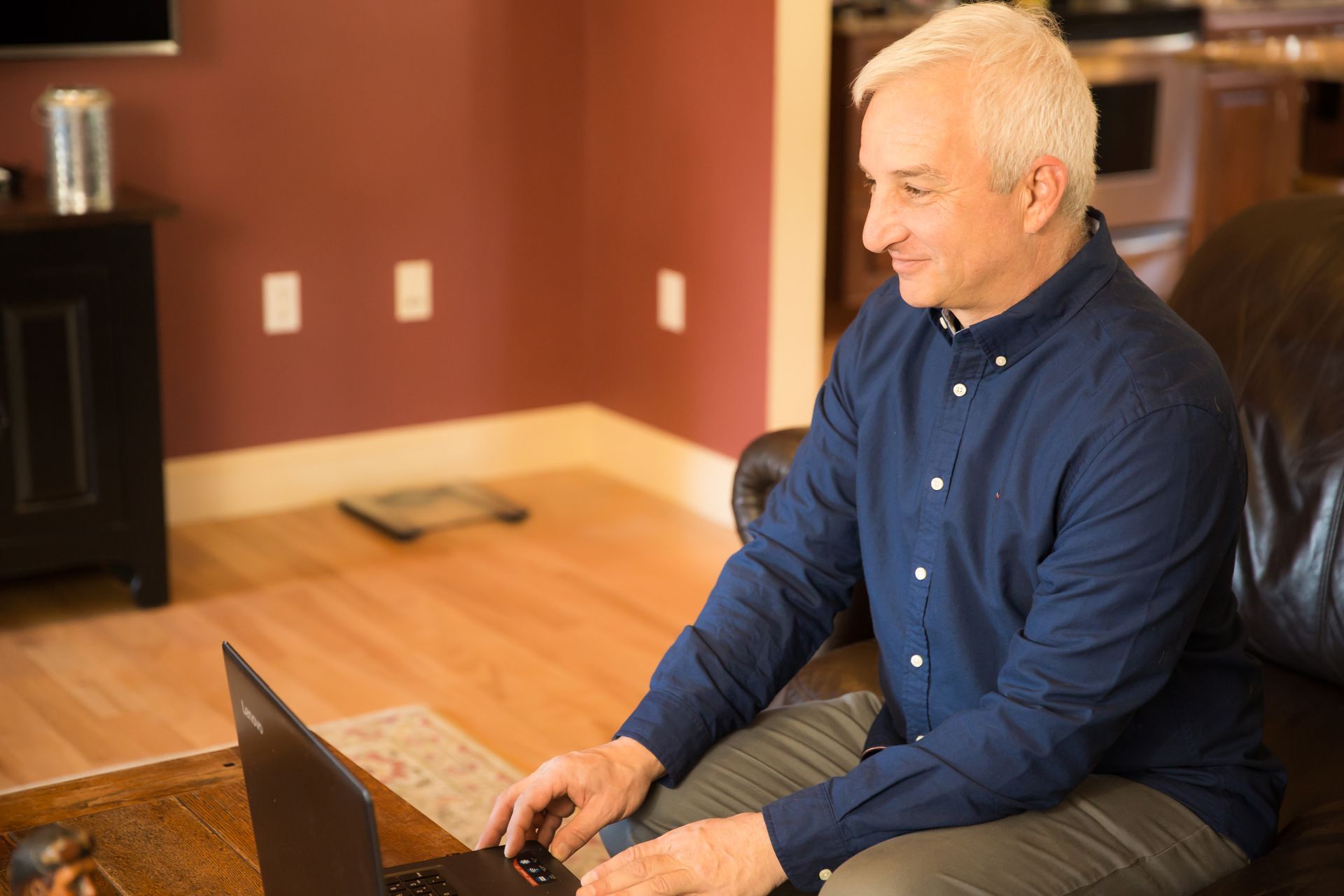 A man is sitting on a couch using a laptop computer.