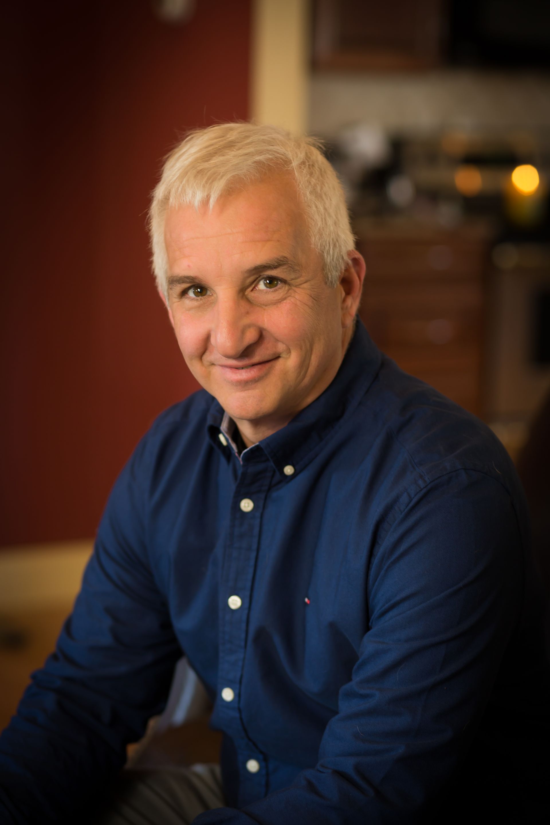 The man is wearing a blue shirt and smiling for the camera.