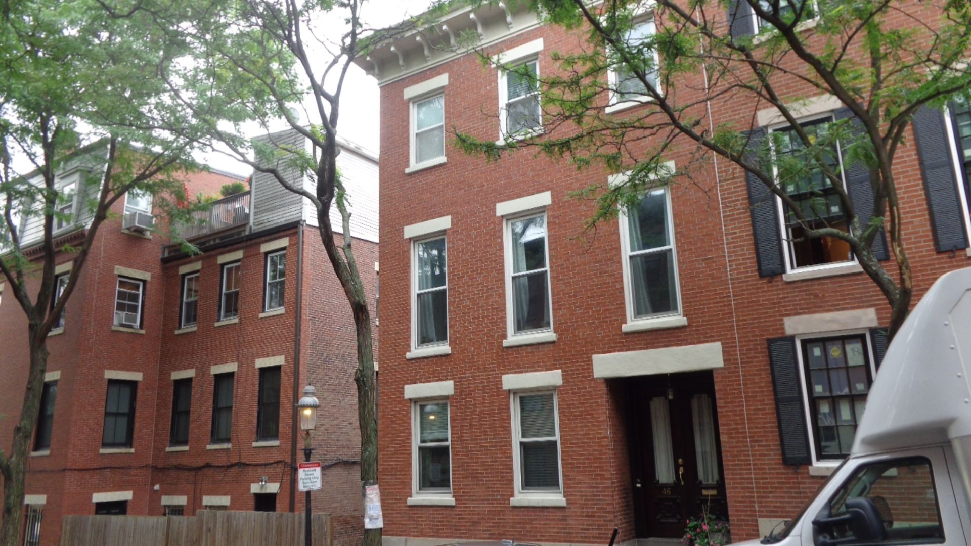 A white van is parked in front of a brick building