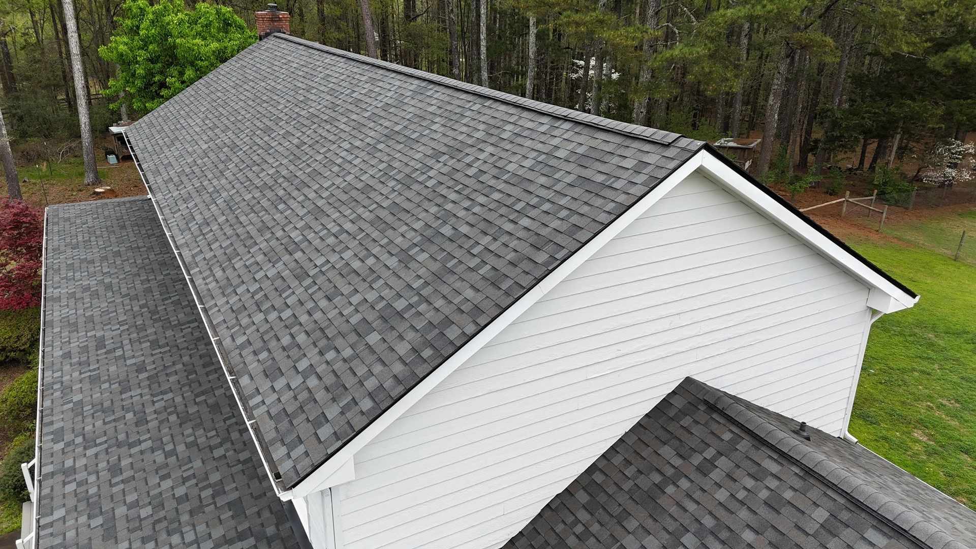 An aerial view of a white house with a gray roof.