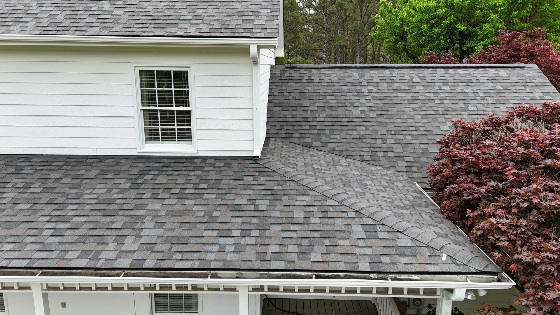 An aerial view of a house with a gray roof and a white siding.