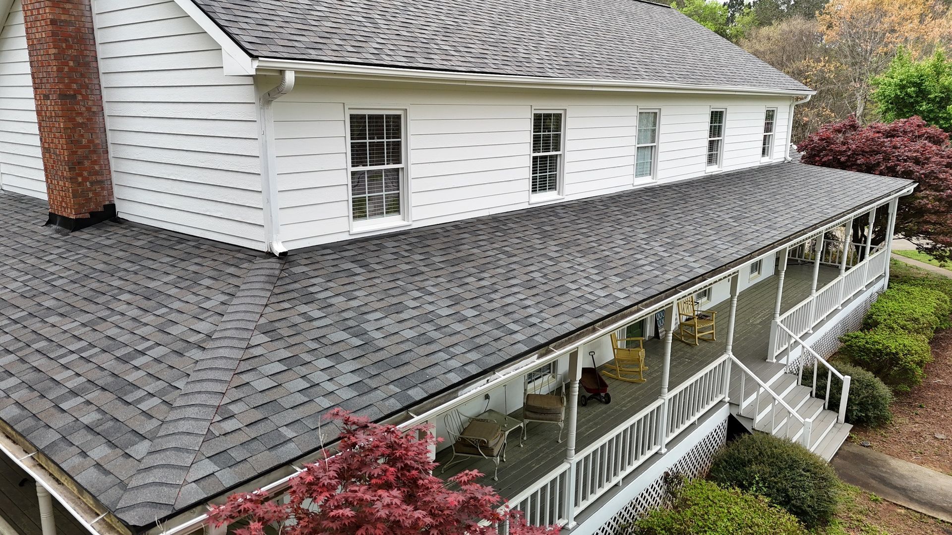 A large white house with a large porch and a gray roof.