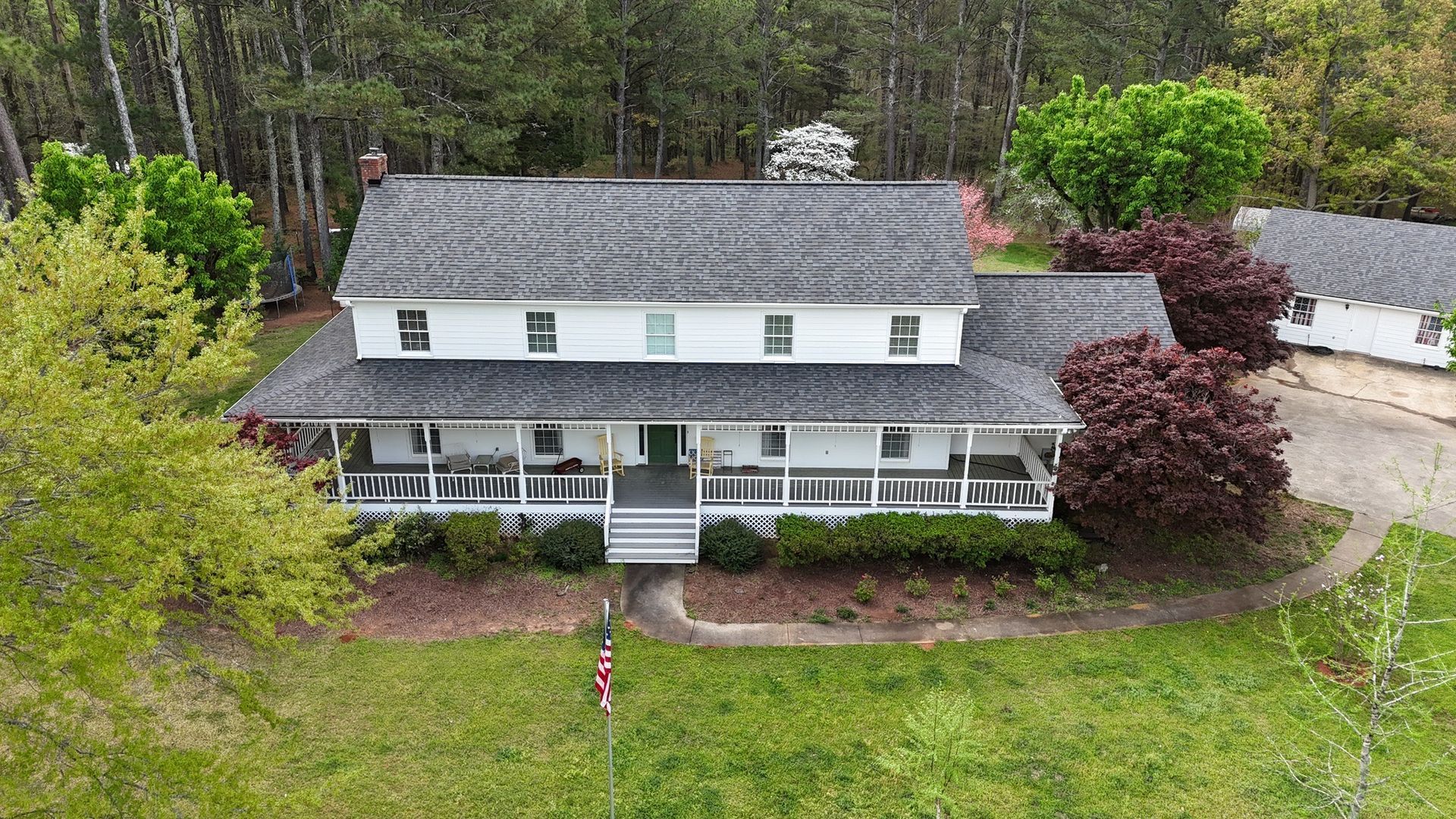 An aerial view of a large white house surrounded by trees.