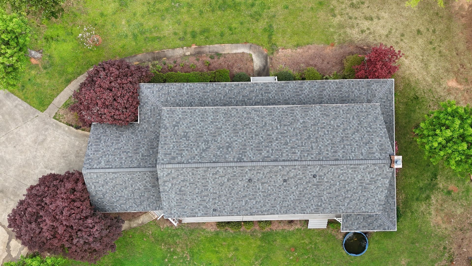 An aerial view of a house with a gray roof and a driveway.
