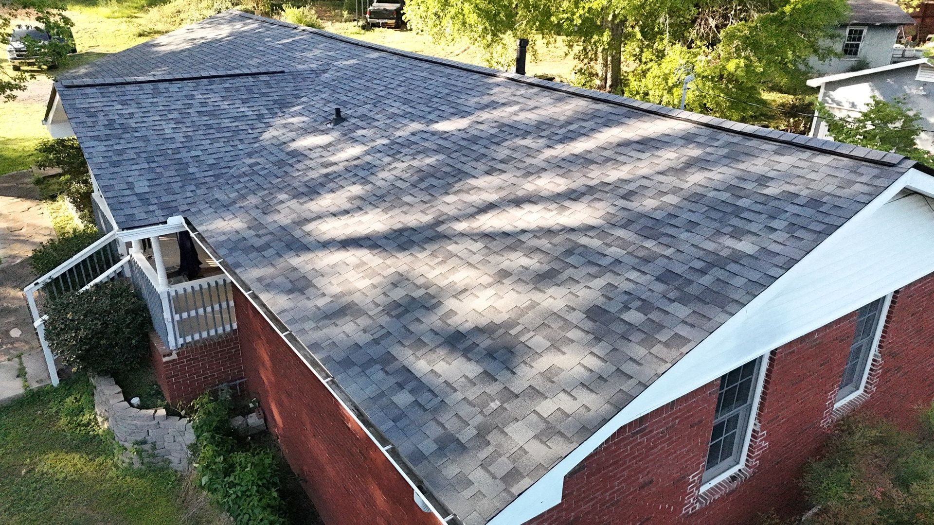 An aerial view of a brick house with a new roof.