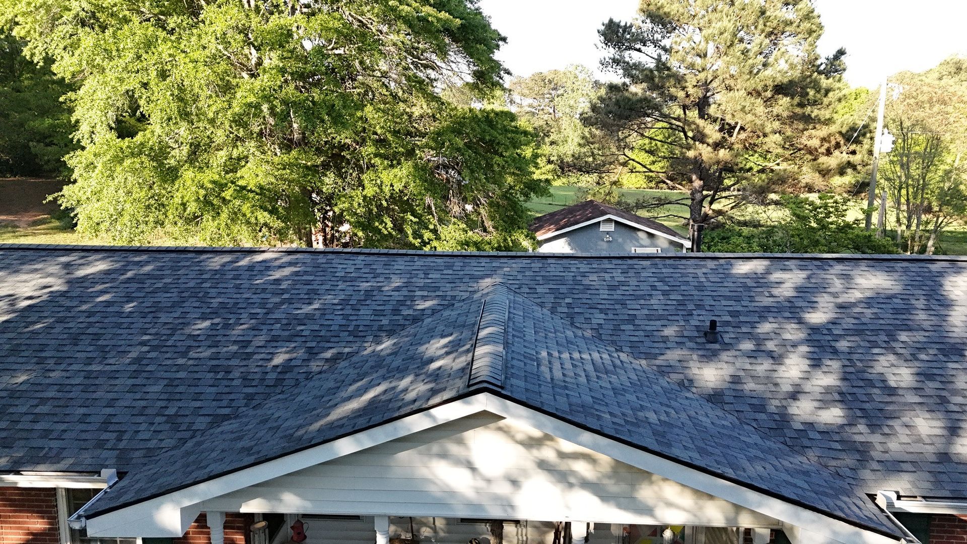 A house with a blue roof and a porch with trees in the background.