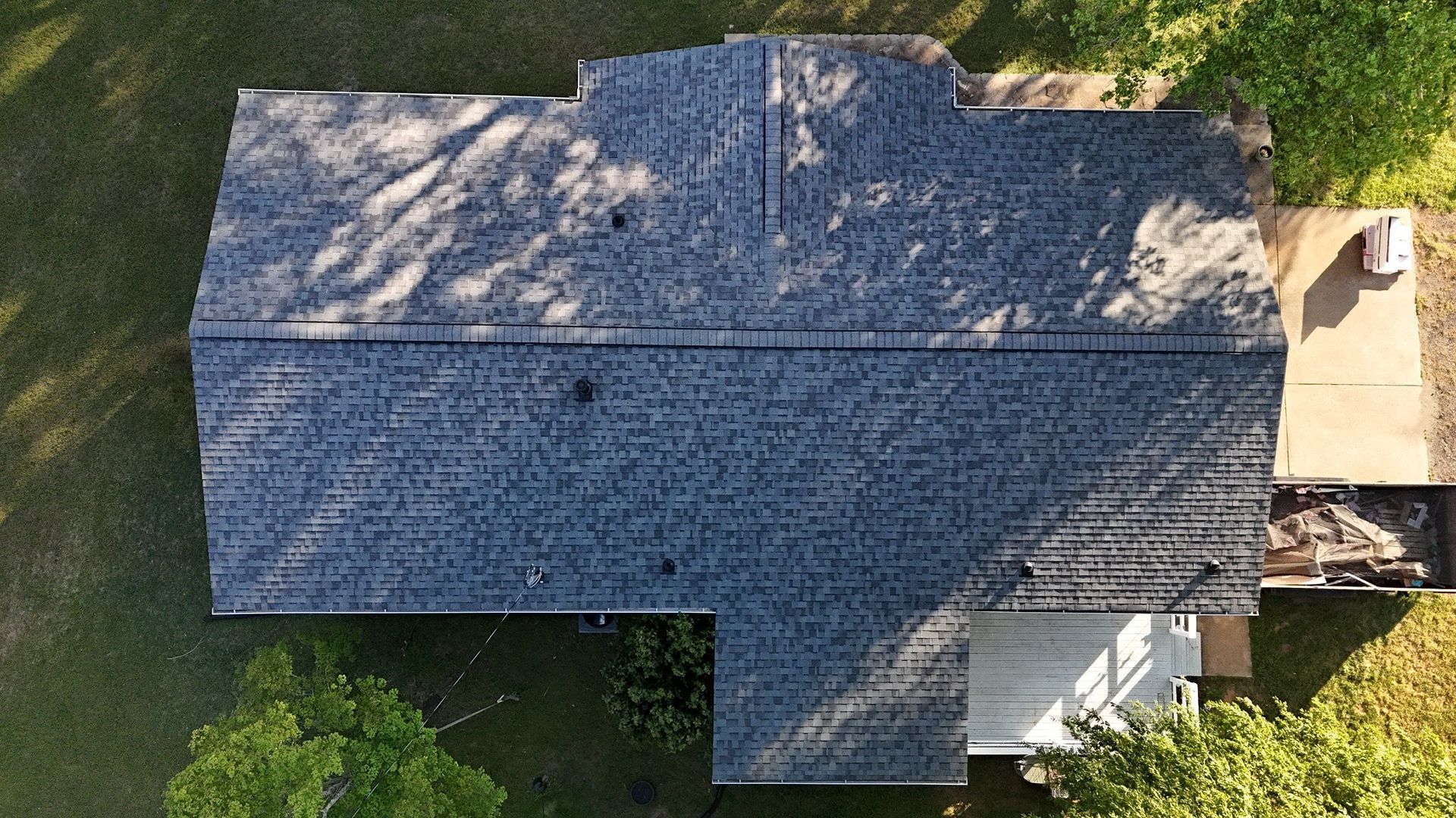 An aerial view of a house with a blue roof surrounded by trees.