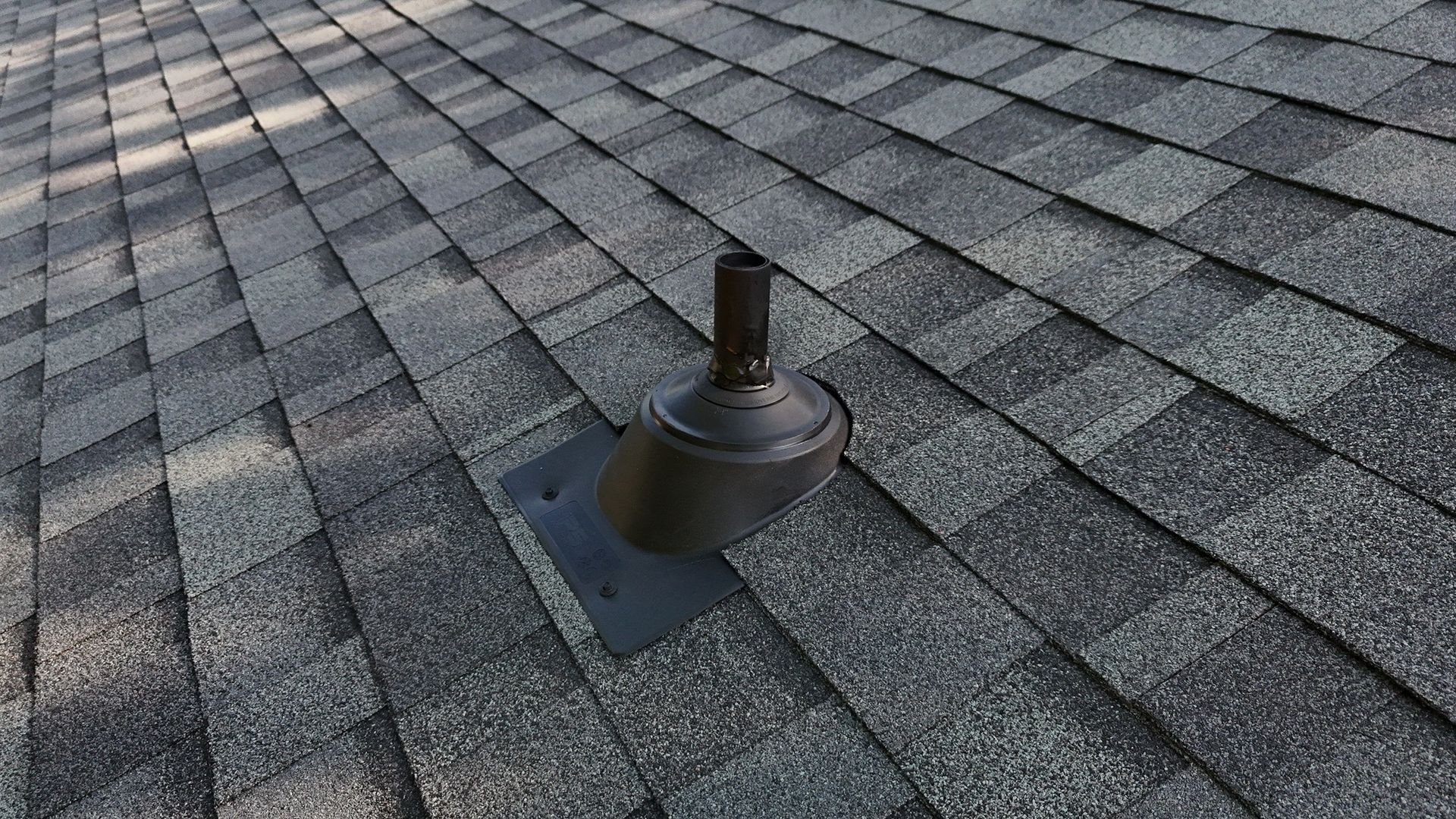 A close up of a roof with shingles and a chimney on it.