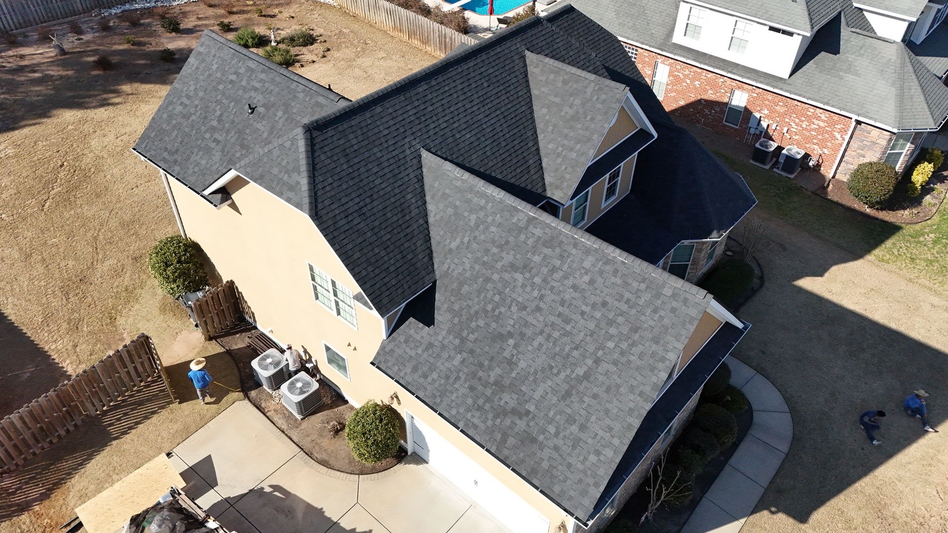 An aerial view of a large house with a black roof.
