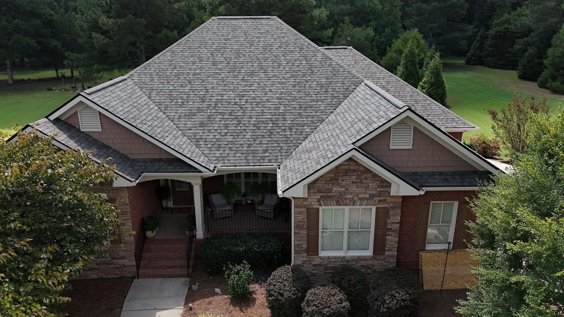 An aerial view of a brick house with a gray roof