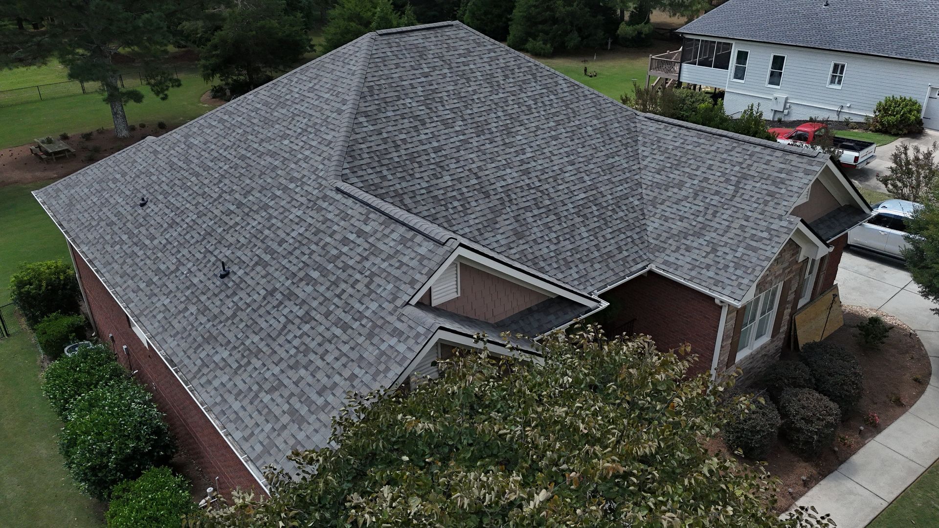 An aerial view of a brick house with a gray roof.
